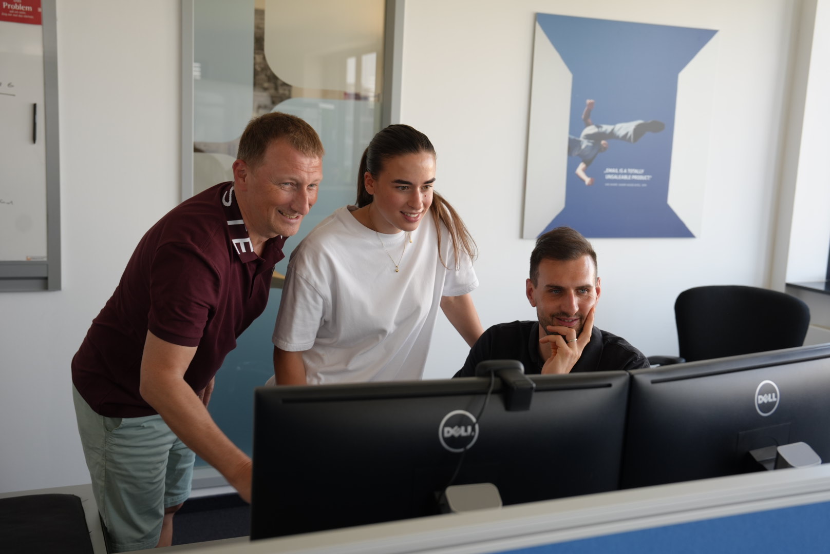 Mitarbeiterfoto: Person am Arbeitsplatz nimmt einen Anruf entgegen, Kopfhörer, konzentrierte Haltung, natürliches Licht. Der Moment kurz vor dem ersten Wort. Büro Darmstadt, zweiter Monitor unscharf im Hintergrund.